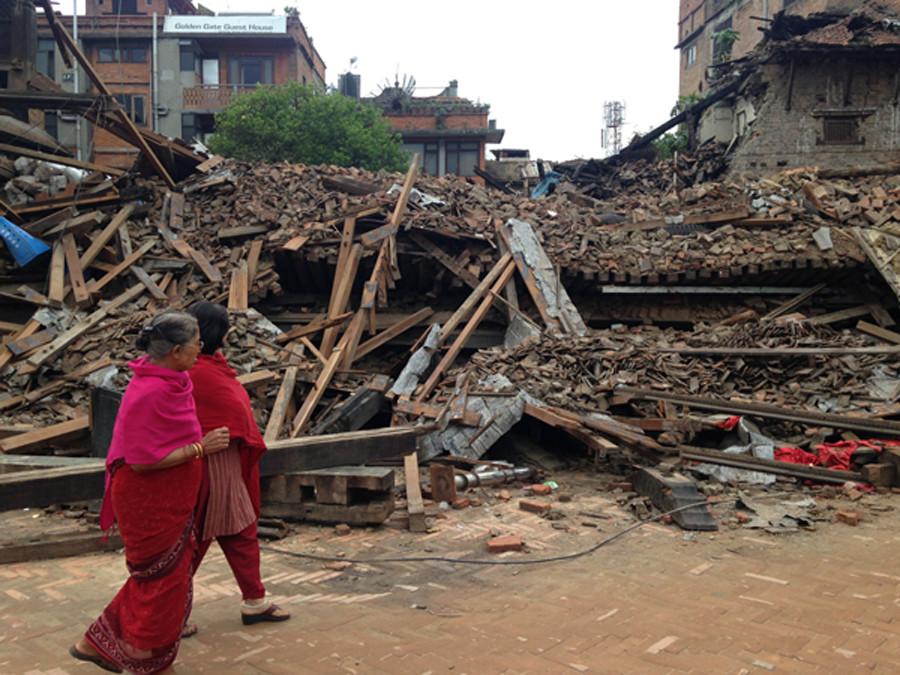 Two women walking past a destroyed building in Bhaktapur, Nepal.