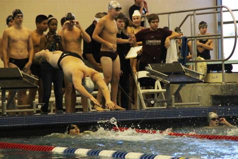 Varsity swimmer leaps from the blocks to put his relay farther ahead.
