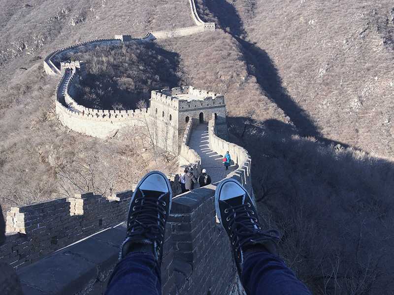 Ally Walters feet dangling over The Great Wall of China