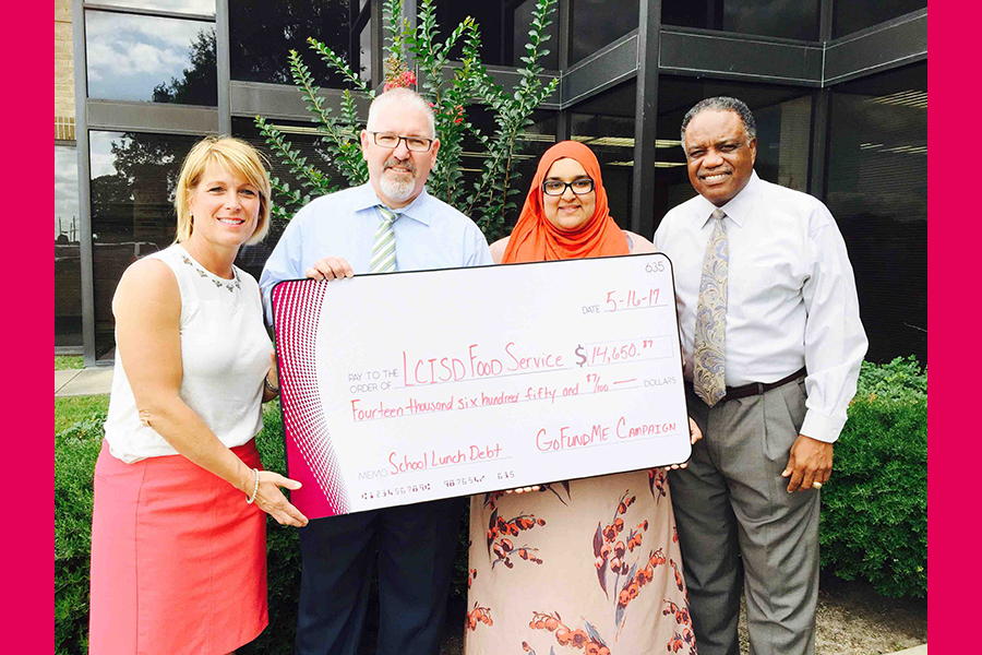 Amina Ishaq and other members holding their check to wipe LCISD lunch debt