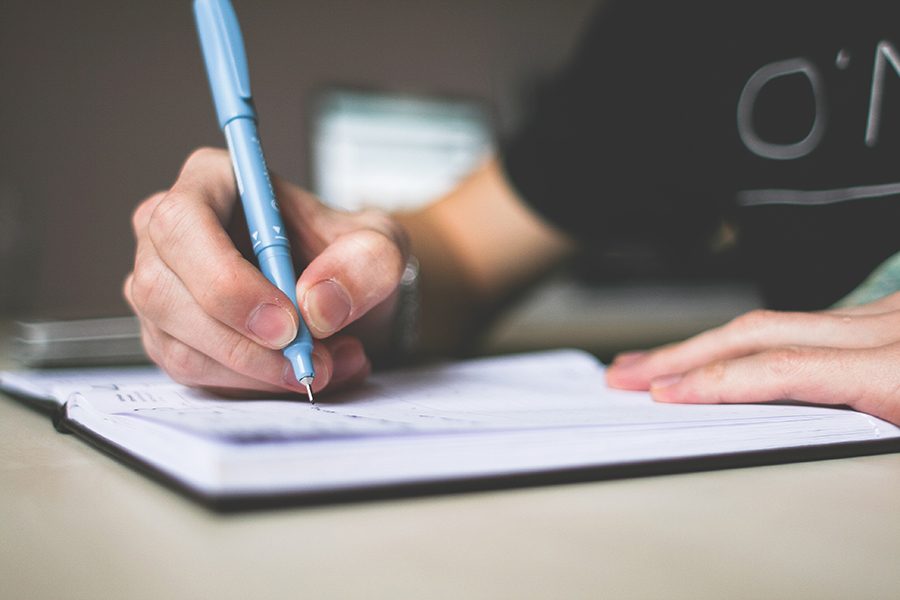 https://www.pexels.com/photo/person-holding-blue-ballpoint-pen-writing-in-notebook-210661/