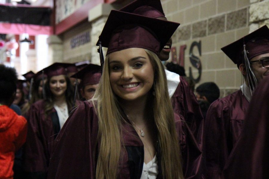 Sarah Cox smiles as she watches her fellow classmates take some of their final steps through the campus.
