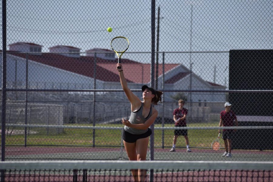 Alexis Frey (12) attempting to make an important serve over the net.