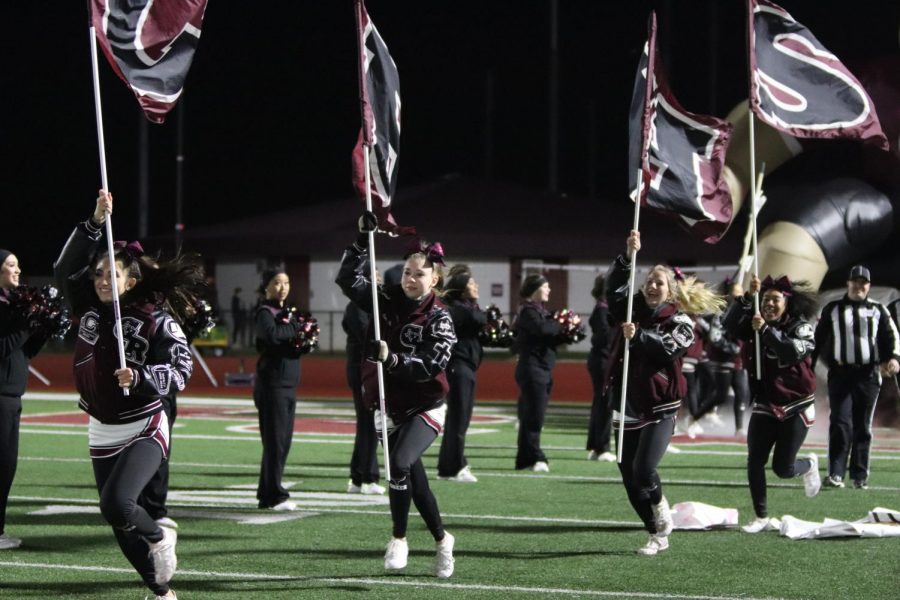 Cheerleaders, Jenna Christoffel(12), Averi Glaze(12), Brooke Heitkamp(10), and Myla Williams(10), run with the GRHS flags to kick off the second half after half time.