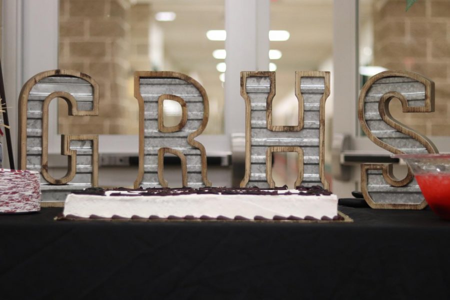 A nice table set up with the celebratory cake and fruit punch in front of letters that spell GRHS.
