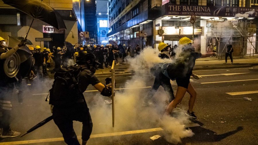 Hong Kong police and protesters clash in the midst of a tear gas haze.