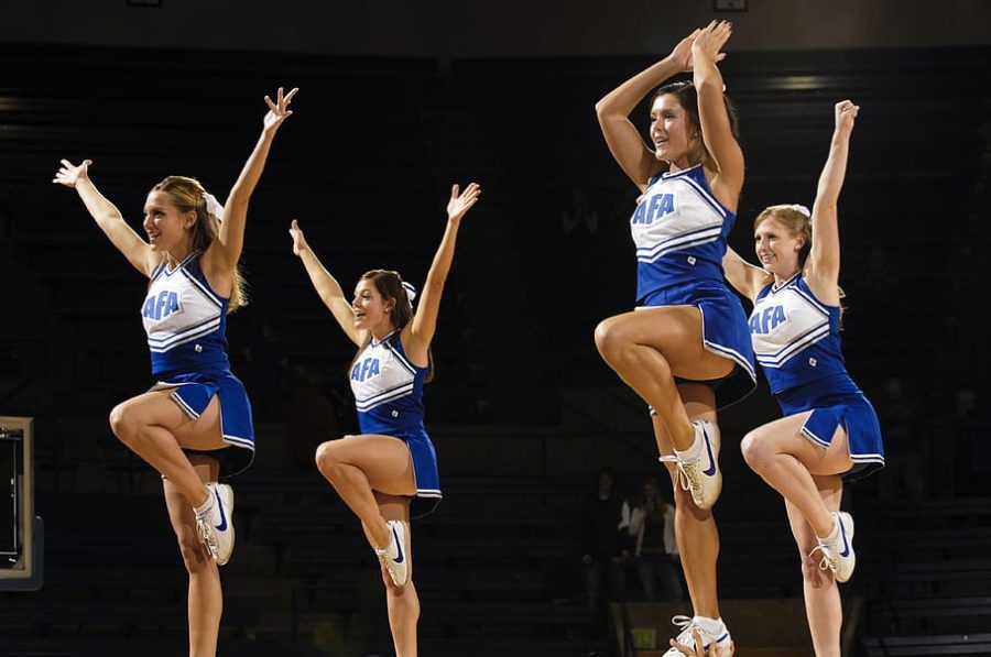 These four college competitive cheerleaders perform to the crowd while in a stunt. 