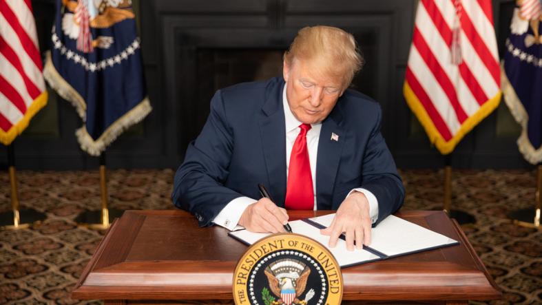 President Donald Trump signing documents to reimpose sanctions on Iran.