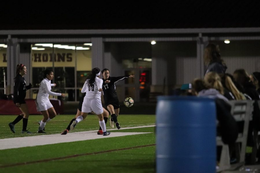 Cassidy Hoang (17) kicking the ball while the rest of the team is on the side lines.