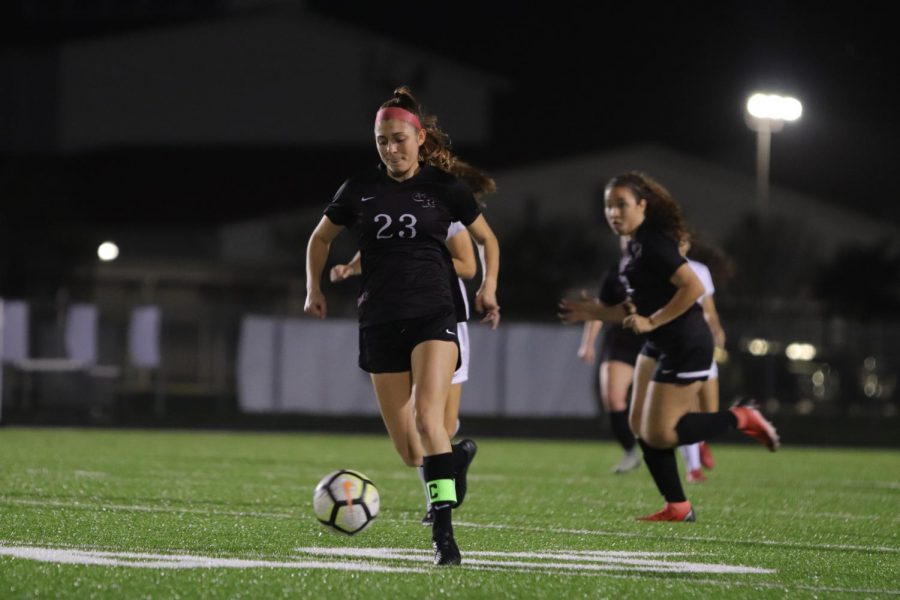 No. 23 Riley Grafe (12) sprinting across the field with the ball, looking for an open pass to her one of her teammates.