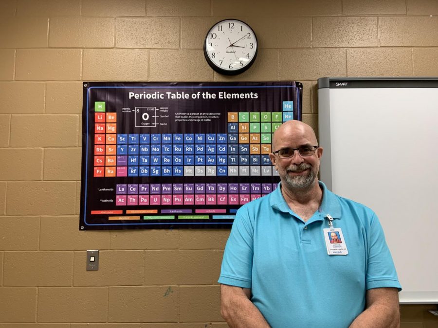 Mr. Sherman, a new science teacher, posing at his Periodic Table poster.